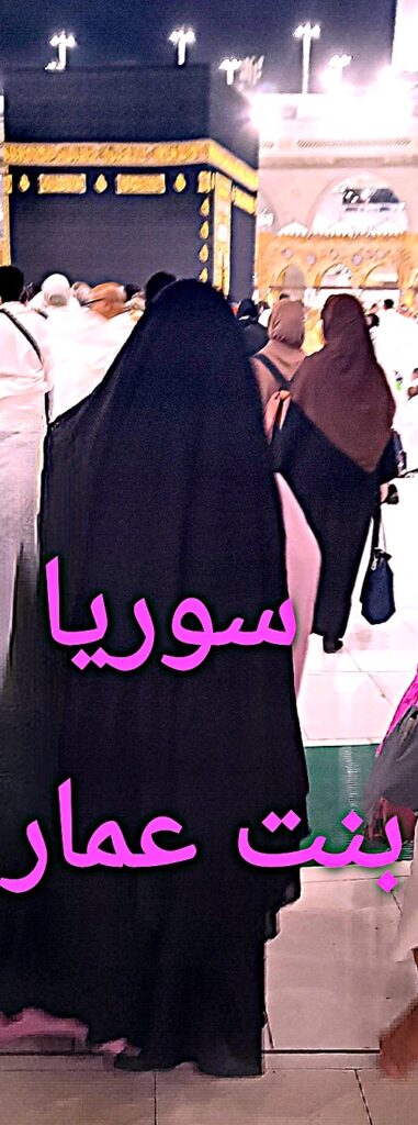 Une femme vêtue d’un jilbab noir marche vers la Kaaba à La Mecque, entourée de pèlerins en prière. Son habit sombre contraste avec la lumière éclatante du Haram.